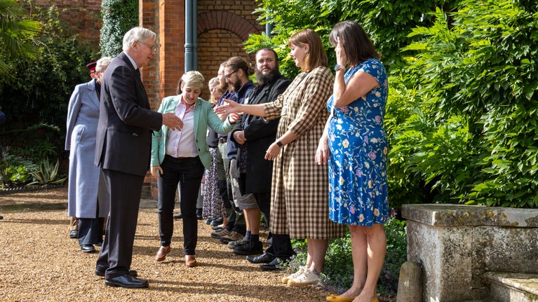 His Royal Highness is greeted by members of staff who are lined up close to the front steps of Peckover House